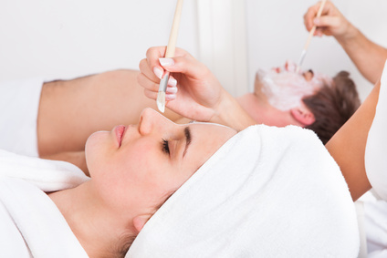 Therapist Applying Facial Mask To Young Couple At Beauty Salon